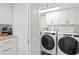 Well-lit laundry room featuring a modern, front-loading Whirlpool washer and dryer and white cabinets at 2425 S Atlantic Ave # 1202A, Daytona Beach Shores, FL 32118