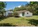 Overgrown backyard with a single-story home featuring a brown roof and white siding, with a sliding glass door at 29505 North, Paisley, FL 32767