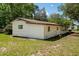 Side view of white-sided single-story home, featuring a brown roof, several windows, and an overgrown yard at 29505 North, Paisley, FL 32767