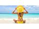 Personal sits on a beautiful white sand beach wearing a large brimmed hat and a bright yellow swim suit at 2967 S Atlantic Ave # 202, Daytona Beach Shores, FL 32118