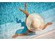 Personal wearing a hat relaxes in the shimmering, clear, cool blue water of the community pool on a bright sunny day at 2967 S Atlantic Ave # 202, Daytona Beach Shores, FL 32118