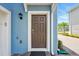 View of front door with sidelights, brown paint, white trim, and exterior lighting at 3049 Meleto Blvd, New Smyrna Beach, FL 32168