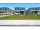 Inviting two-story blue home featuring a well-manicured lawn and a cozy covered porch seating area at 3049 Meleto Blvd, New Smyrna Beach, FL 32168