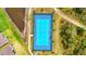 Aerial view of a community tennis court with blue surface and surrounded by lush green space and a small pond at 3049 Meleto Blvd, New Smyrna Beach, FL 32168