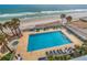 Aerial view of a pool and hot tub surrounded by lounge chairs near the ocean and palm trees at 3145 S Atlantic Ave # 503, Daytona Beach Shores, FL 32118