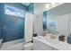 Bright bathroom featuring a blue tiled wall, white fixtures, and natural light from the window above the tub at 3229 Medici Blvd, New Smyrna Beach, FL 32168