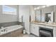 Stylish bathroom with a soaking tub, vanity area with storage, and a large window for natural light at 3229 Medici Blvd, New Smyrna Beach, FL 32168