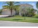 Home featuring a three-car garage, covered entry, well-kept lawn and tropical landscaping at 3229 Medici Blvd, New Smyrna Beach, FL 32168