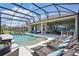 A screened pool is surrounded by lounge chairs and outdoor living areas with a covered kitchen at 3229 Medici Blvd, New Smyrna Beach, FL 32168
