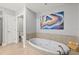 Bathroom featuring a soaking tub, neutral tile surround, and decorative artwork at 3245 S Atlantic Ave # 304, Daytona Beach Shores, FL 32118