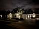 Nighttime view of charming home with stone accents, a paver driveway, and beautiful landscaping at 3322 Modena Way, New Smyrna Beach, FL 32168