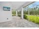 Covered screened patio featuring neutral pavers, outdoor TV, and a view of lush green landscaping at 3322 Modena Way, New Smyrna Beach, FL 32168