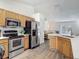 Functional kitchen with stainless steel appliances, wood cabinetry, an island with sink, and a view into the living area at 400 Landress Ln, Deland, FL 32724
