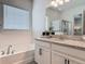 Bright bathroom with double sink vanity, granite counters, a large mirror, and a soaking tub at 409 Nowell Loop, Deland, FL 32724