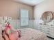 Cozy bedroom featuring pink walls, board and batten trim, white dresser and an adorable princess themed bedding at 409 Nowell Loop, Deland, FL 32724