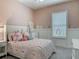 Cozy bedroom with pink walls, a plush bed with a patterned quilt, and soft natural light from the window at 409 Nowell Loop, Deland, FL 32724