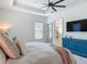 Bright main bedroom with tray ceiling, ceiling fan, blue dresser and ensuite bathroom with glass shower at 409 Nowell Loop, Deland, FL 32724