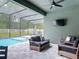 Screened-in pool area featuring a covered patio with comfortable seating and a ceiling fan at 409 Nowell Loop, Deland, FL 32724