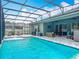 Inviting screened-in pool with a spacious deck, lounge chairs, and lush landscaping at 409 Nowell Loop, Deland, FL 32724