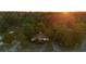 Aerial view of the home nestled among mature trees in a serene setting at sunset at 409 S Sparkman Ave, Orange City, FL 32763