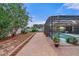 Brick-paved walkway leading to a screened pool area with lush landscaping and lounging area at 4604 Barbados Loop, Clermont, FL 34711