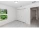 Bright bedroom featuring white walls, gray wood-look flooring, closet and view into hallway at 544 E Voorhis Ave, Deland, FL 32724