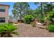 Serene backyard featuring a hammock, fire pit with chairs, lush greenery, and a storage shed at 5496 S Nova Rd, Port Orange, FL 32127
