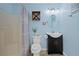 Well-lit bathroom featuring a shower, toilet, vanity with sink, and decorative accents against a pale blue wall at 5496 S Nova Rd, Port Orange, FL 32127