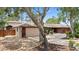 Single-story brick home with mature tree, driveway, and two-car garage at 5496 S Nova Rd, Port Orange, FL 32127