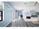 Hallway with wood-look tile flooring leading to an open-concept kitchen with white cabinetry and a microwave at 5496 S Nova Rd, Port Orange, FL 32127