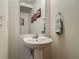 Stylish half bath featuring a pedestal sink, decorative mirror, and modern fixtures at 564 Mount Olympus Blvd, New Smyrna Beach, FL 32168