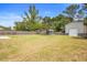 Large grassy backyard featuring a metal shed, a small wood shed, and a wood fence on a sunny day at 6509 Lake Lerla Dr, Apopka, FL 32712