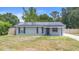 Front exterior of the home with solar panels on the roof, grassy lawn, and black window shutters at 6509 Lake Lerla Dr, Apopka, FL 32712