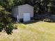A large metal shed with a garage door is placed in the grassy backyard, surrounded by lush trees at 6509 Lake Lerla Dr, Apopka, FL 32712