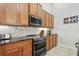 Well-lit kitchen showcases wooden cabinets, black appliances, and tile backsplash at 6820 Vintage Ln, Port Orange, FL 32128