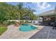 Inviting backyard pool area with lush landscaping, waterfall feature, covered patio, and brick pavers at 6820 Vintage Ln, Port Orange, FL 32128