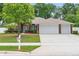 Charming brick home featuring a three-car garage and well-manicured lawn with mature landscaping at 703 Elkhorn Fern Ln, Deland, FL 32720
