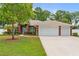 Charming brick home with a well-manicured lawn, mature trees, and a three car garage at 703 Elkhorn Fern Ln, Deland, FL 32720