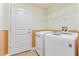 This laundry room features a modern washer and dryer, wooden accent, and white shelving at 703 Elkhorn Fern Ln, Deland, FL 32720