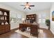 Home office with hardwood flooring, shuttered windows, and built in bookcase and desk at 703 Elkhorn Fern Ln, Deland, FL 32720