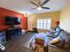 Living room features a ceiling fan, hardwood floors, a large sofa, and a mounted television on a red accent wall at 783 Shropshire Loop, Sanford, FL 32771