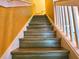 An upward view of the wooden stairway with white railing and yellow walls leading to the upper level at 783 Shropshire Loop, Sanford, FL 32771