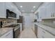 Galley kitchen featuring stainless steel appliances, granite countertops, and sleek white cabinetry at 834 Sugar House Dr, Port Orange, FL 32129