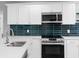 Modern kitchen boasts white cabinets, stainless steel appliances, white countertops, and unique blue backsplash at 9720 Fairway Cir, Leesburg, FL 34788