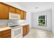 Well-lit kitchen featuring white appliances, wood cabinets, and tile flooring at 1120 W Glen Falls Rd, Deland, FL 32720