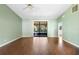 Large, empty living room featuring laminate flooring, ceiling fan, and sliding glass doors to outdoor patio at 1120 W Glen Falls Rd, Deland, FL 32720