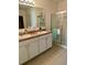 Bathroom featuring double sinks, white cabinets, granite counters and glass-enclosed tiled shower at 119 Fishermans Cove Dr, Edgewater, FL 32141