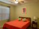 Comfortable bedroom features a ceiling fan, a large bed with bright orange quilt, and window at 119 Fishermans Cove Dr, Edgewater, FL 32141