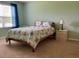 Bedroom with wooden bed frame, colorful linens, a blue curtain, and bedside table at 119 Fishermans Cove Dr, Edgewater, FL 32141