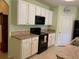 Updated kitchen boasts white cabinetry, black appliances, tile floors, and laminate countertops at 119 Fishermans Cove Dr, Edgewater, FL 32141